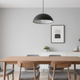 Modern home lighting solutions featuring a stylish black pendant lamp over a wooden dining table in a minimalist space.